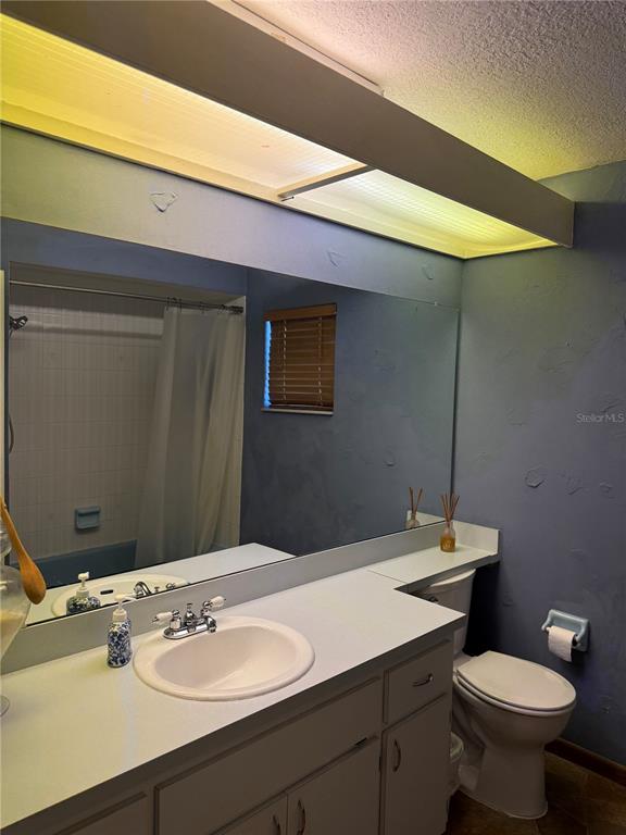 A bathroom features a single vanity with a white countertop, a large mirror, and a toilet — 9231 ELDRIDGE ROAD, SPRING HILL, FL