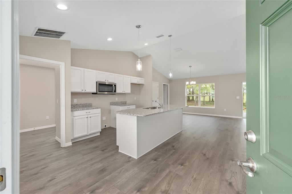 A view from a doorway into an open-concept kitchen and living area with gray flooring — 3853 SW SOUNDVIEW DRIVE, DUNNELLON, FL