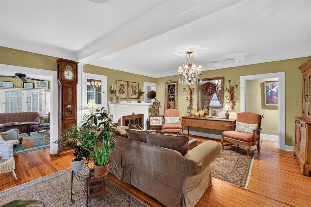 A living room features a fireplace, a grandfather clock, a chandelier, and hardwood floors — 1046 N MCDONALD STREET, MOUNT DORA, FL