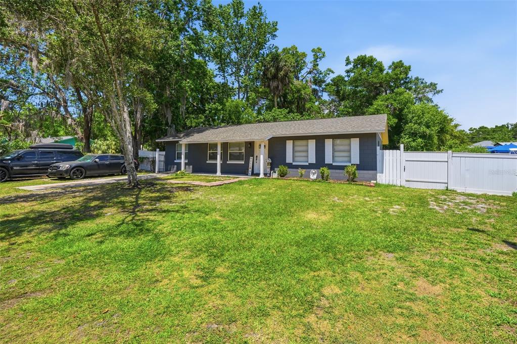 A single-story gray house with white shutters and a white fence sits on a lawn — 8509 W KIPLING LANE, HOMOSASSA, FL