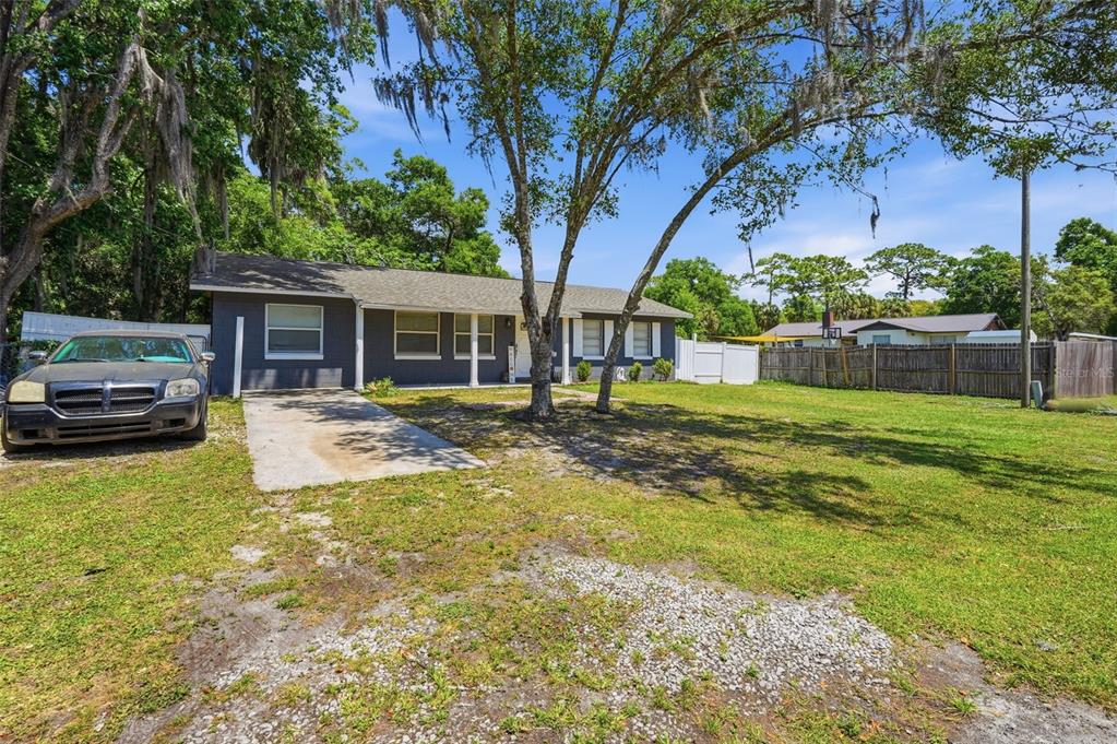 A single-story gray house with a concrete driveway and a large front yard — 8509 W KIPLING LANE, HOMOSASSA, FL