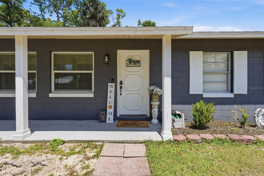 The exterior of a house features a gray block wall, a white front door, and columns — 8509 W KIPLING LANE, HOMOSASSA, FL