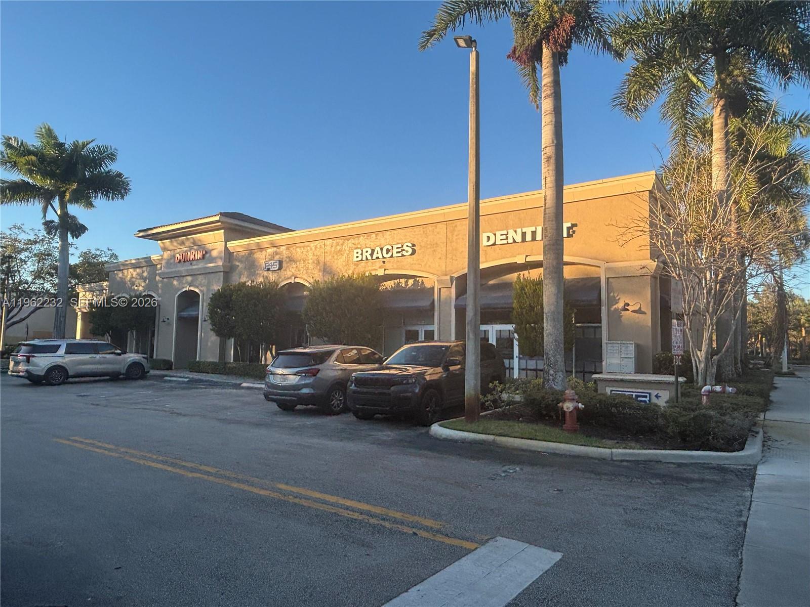 A commercial building with a Dunkin' and dental office features a parking lot and palms — 2575 Glades Cir, Weston FL 33327, WESTON, FL