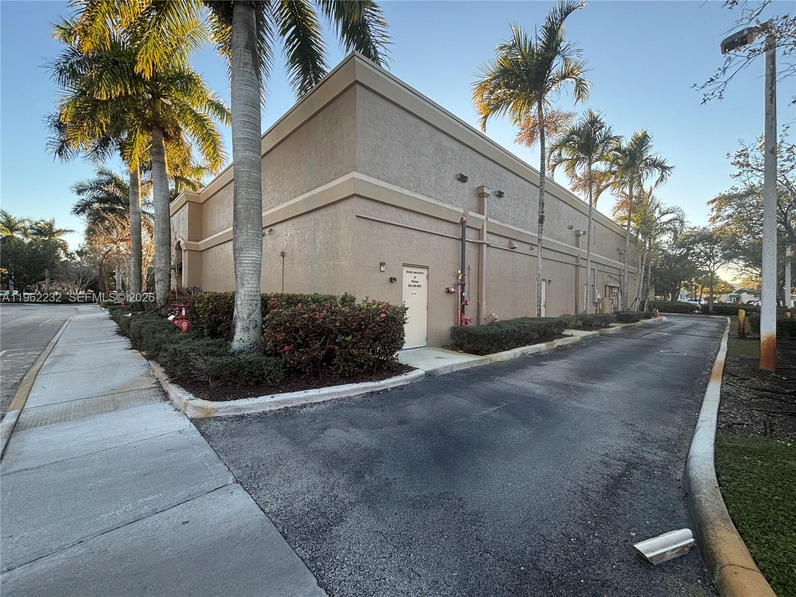The exterior of a tan commercial building features palm trees, a sidewalk, and a driveway — 2575 Glades Cir, Weston FL 33327, WESTON, FL