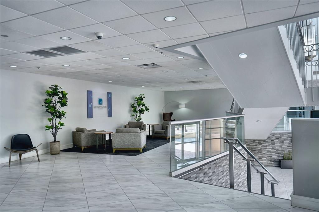 A modern lobby features a seating area, tiled floors, and a staircase with glass railings — 151 E WASHINGTON STREET UNIT 525, ORLANDO, FL