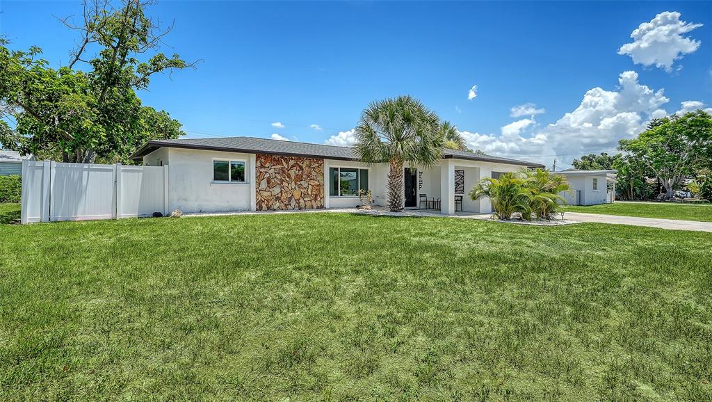 A single-story house with a stone facade, white siding, and a palm tree in front — 1302 MANGO AVENUE, VENICE, FL