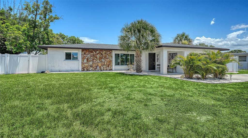 A single-story house with a stone facade, white siding, and a palm tree in front — 1302 MANGO AVENUE, VENICE, FL