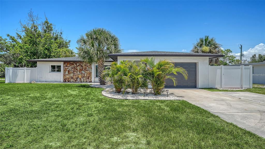 A single-story house with a stone facade, palm trees, and a concrete driveway — 1302 MANGO AVENUE, VENICE, FL