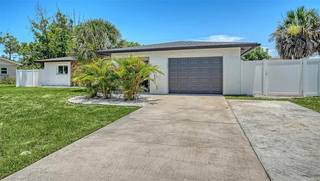 A white house with a gray garage door and a concrete driveway under a blue sky — 1302 MANGO AVENUE, VENICE, FL