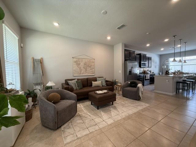 A living room features a brown sofa, two armchairs, and an open kitchen with island — 5030 CASPIAN STREET, ST CLOUD, FL