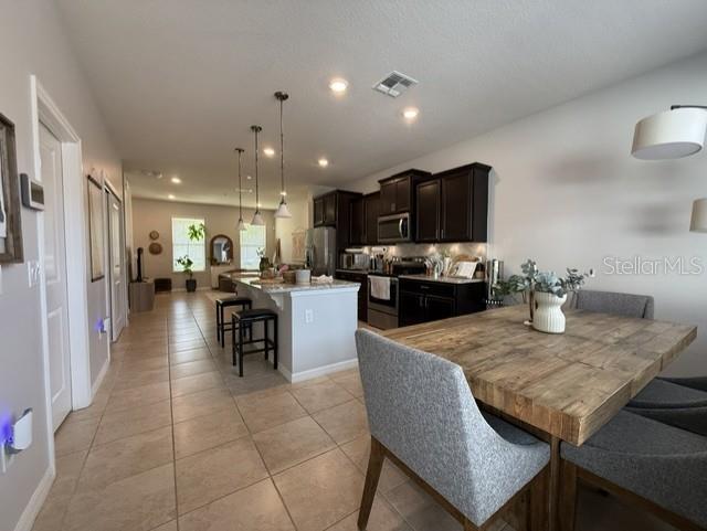 A kitchen with dark cabinets and a central island overlooks a dining area — 5030 CASPIAN STREET, ST CLOUD, FL