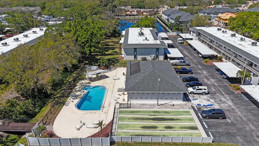 An aerial view shows a swimming pool, shuffleboard courts, and apartment buildings with parking lots — 7700 92ND STREET UNIT 207, SEMINOLE, FL