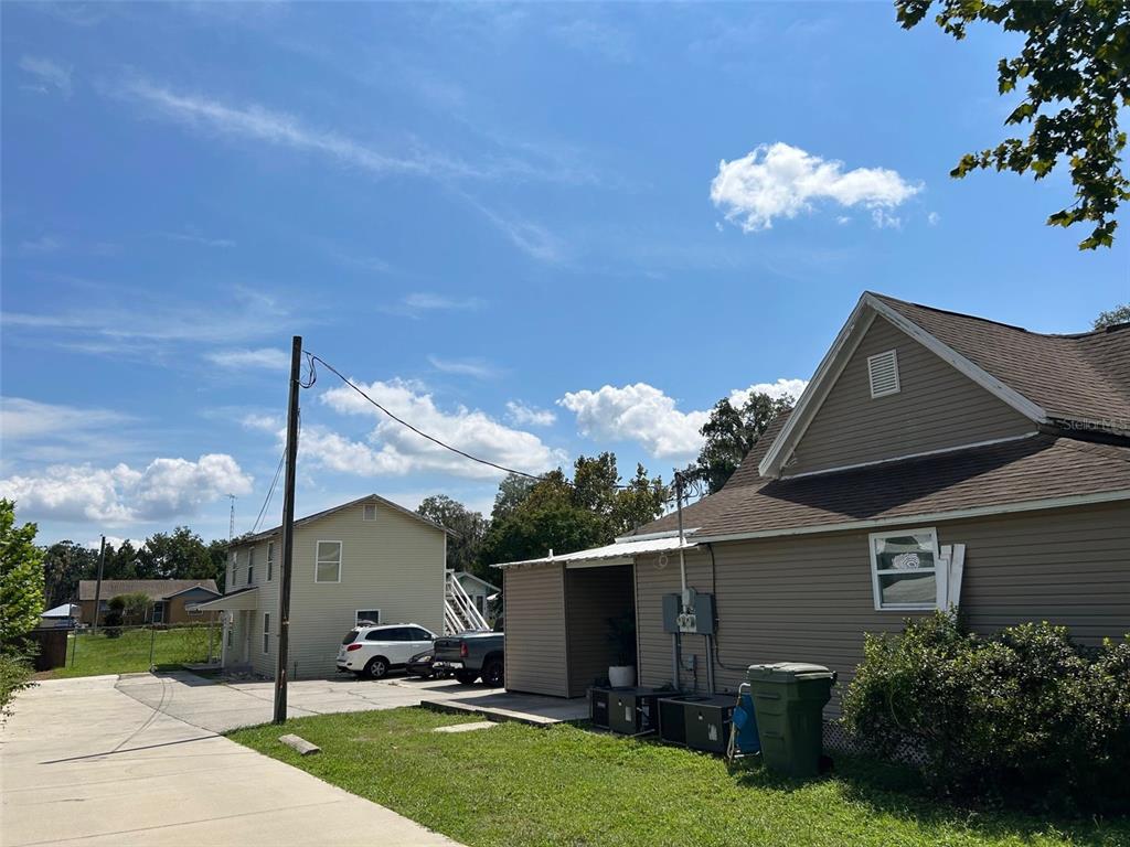 An exterior view shows two houses with beige siding, a concrete driveway, and a grassy yard — 400 S 6TH STREET, LEESBURG, FL