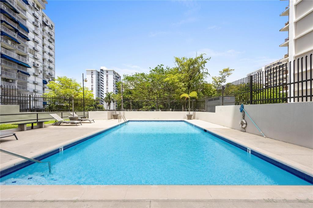 An outdoor rectangular swimming pool is surrounded by a concrete deck and a metal fence — 253 CHILE UNIT 1-C, SAN JUAN, PR
