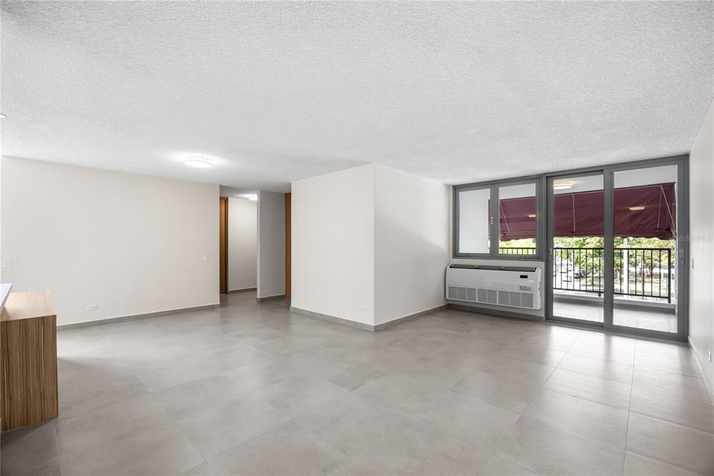 An empty living area features light-colored tile flooring, white walls, and a sliding glass door — 253 CHILE UNIT 1-C, SAN JUAN, PR