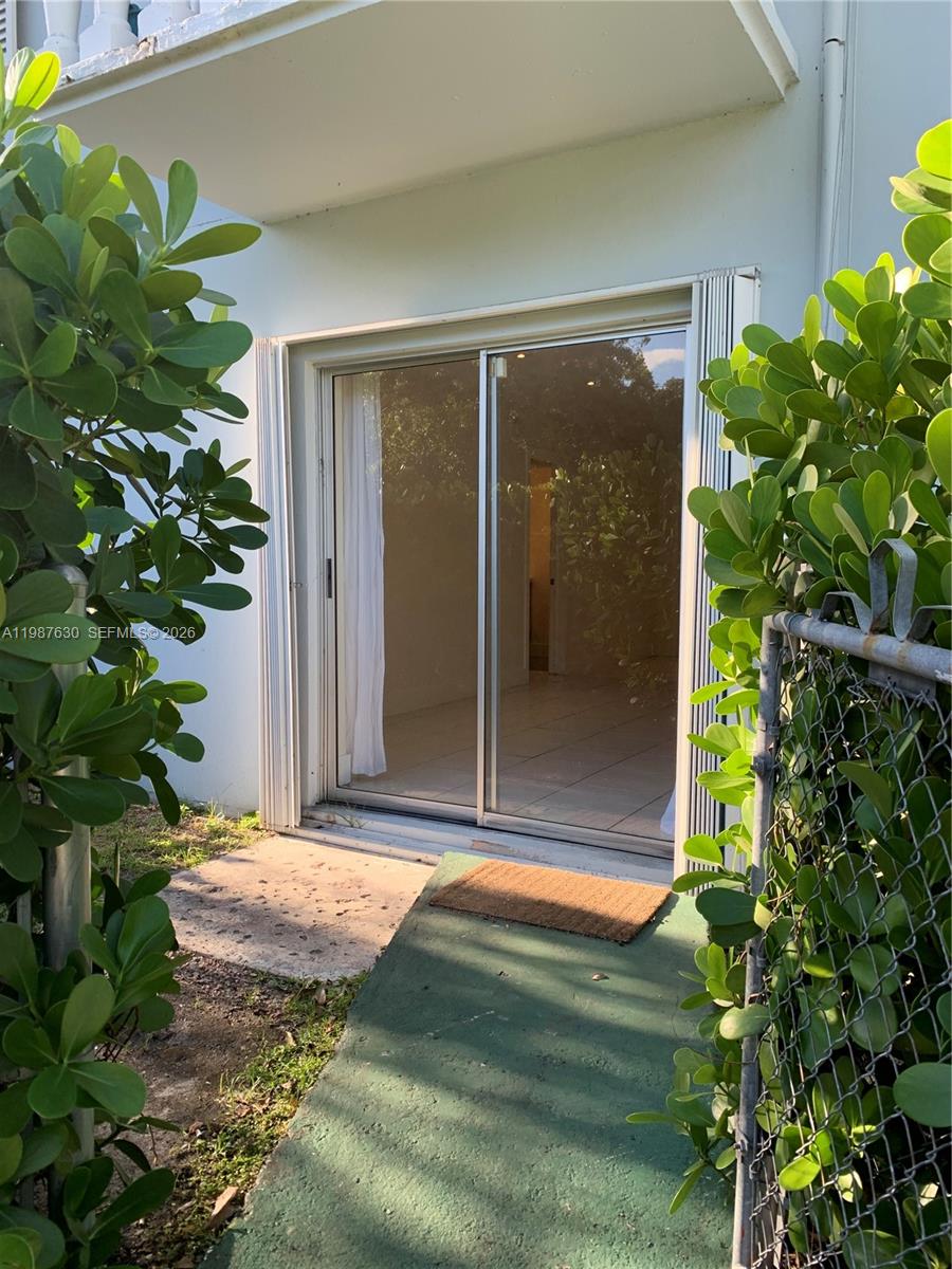 A sliding glass door leads from a small outdoor patio into a tiled interior room — 1200 Mariposa Ave # E104, Coral Gables FL 33146, CORAL GABLES, FL