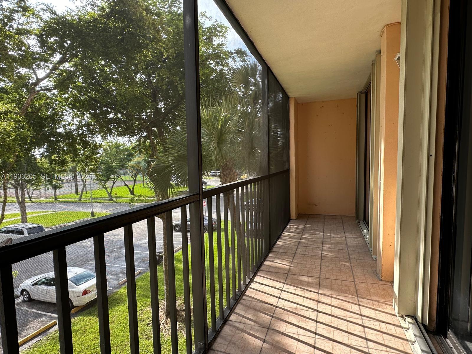 A screened-in balcony features tiled flooring, metal railings, and a view of a parking lot — 8420 SW 133rd Ave Rd # 317, Miami FL 33183, MIAMI, FL