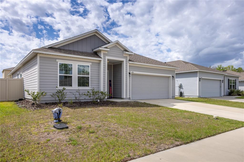 A single-story suburban house with light gray siding, a two-car garage, and a front lawn — 670 NW 243RD TERRACE, NEWBERRY, FL