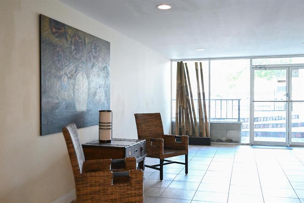 A lobby area features wicker chairs, a small chest, a large painting, and bamboo stalks — 3527 NE 168TH STREET UNIT 208, NORTH MIAMI BEACH, FL