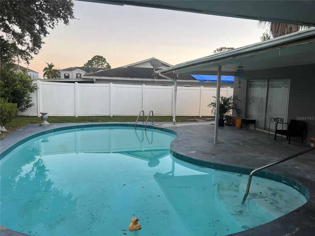 A backyard features a kidney-shaped swimming pool with a concrete patio and white vinyl fencing — 2421 ARCHER BOULEVARD, ORLANDO, FL