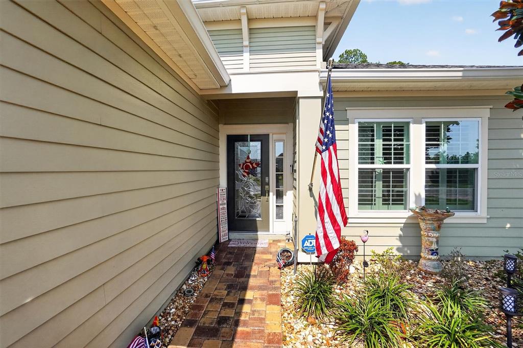 The exterior of a house features tan siding, a brick walkway, and an American flag — 194 ANGUILLA BOULEVARD, ST AUGUSTINE, FL