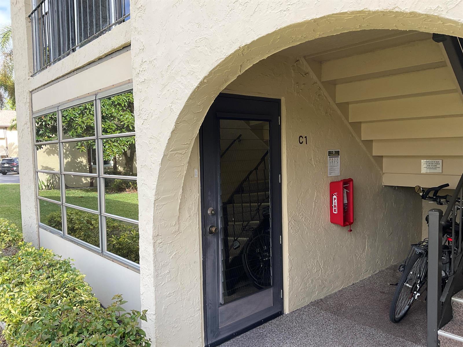 An exterior view of a building entrance labeled C1 with a fire extinguisher and bicycle — 334 Pine Ridge Circle # 1, FL 33463, FL