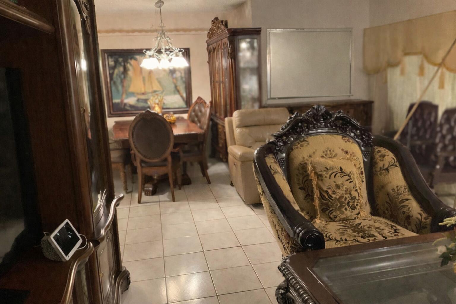 A dining area and living room featuring ornate wooden furniture, tiled floors, and a chandelier — 334 Pine Ridge Circle # 1, FL 33463, FL