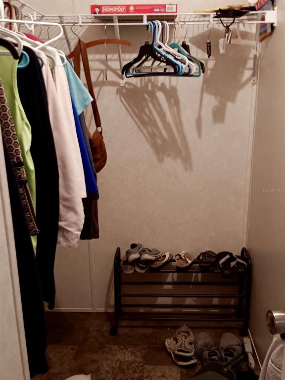 A walk-in closet features hanging clothes, a shoe rack, and a wire storage shelf — 17749 SE 156TH PLACE ROAD, WEIRSDALE, FL
