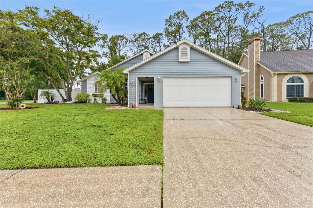 A single-story house with blue siding, a two-car garage, and a concrete driveway — 7226 HUMMINGBIRD LANE, NEW PORT RICHEY, FL