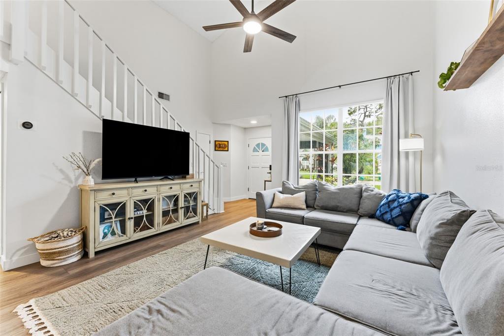 A living room features a grey sectional sofa, a television on a console, and stairs — 7226 HUMMINGBIRD LANE, NEW PORT RICHEY, FL