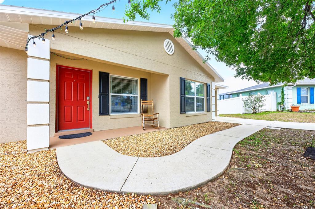 A tan house exterior features a red front door, black shutters, and a curved walkway — 337 WINDRIDGE PLACE, TAVARES, FL