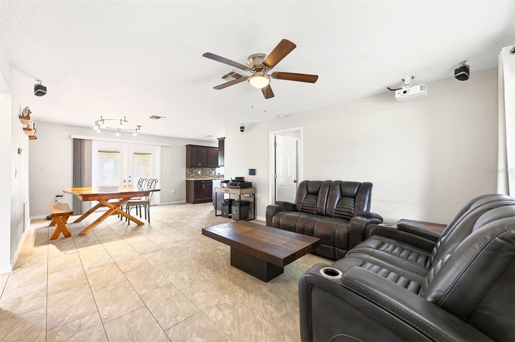 A living room with tile floors, a ceiling fan, and dark leather furniture — 337 WINDRIDGE PLACE, TAVARES, FL