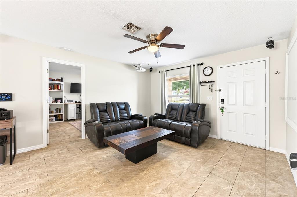 A living room features two dark leather loveseats, a coffee table, and tile flooring — 337 WINDRIDGE PLACE, TAVARES, FL