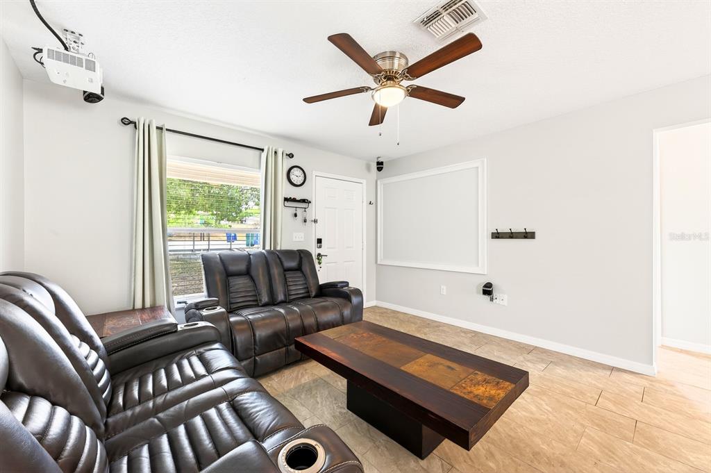 A living room features dark leather recliners, a wooden coffee table, and a ceiling fan — 337 WINDRIDGE PLACE, TAVARES, FL