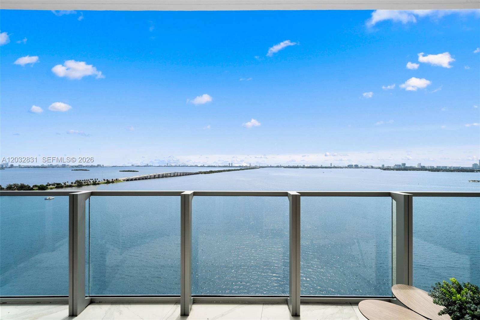 A balcony with glass railings overlooks a large body of water and a distant bridge — 2900 NE 7th Ave # 1902, Miami FL 33137, MIAMI, FL