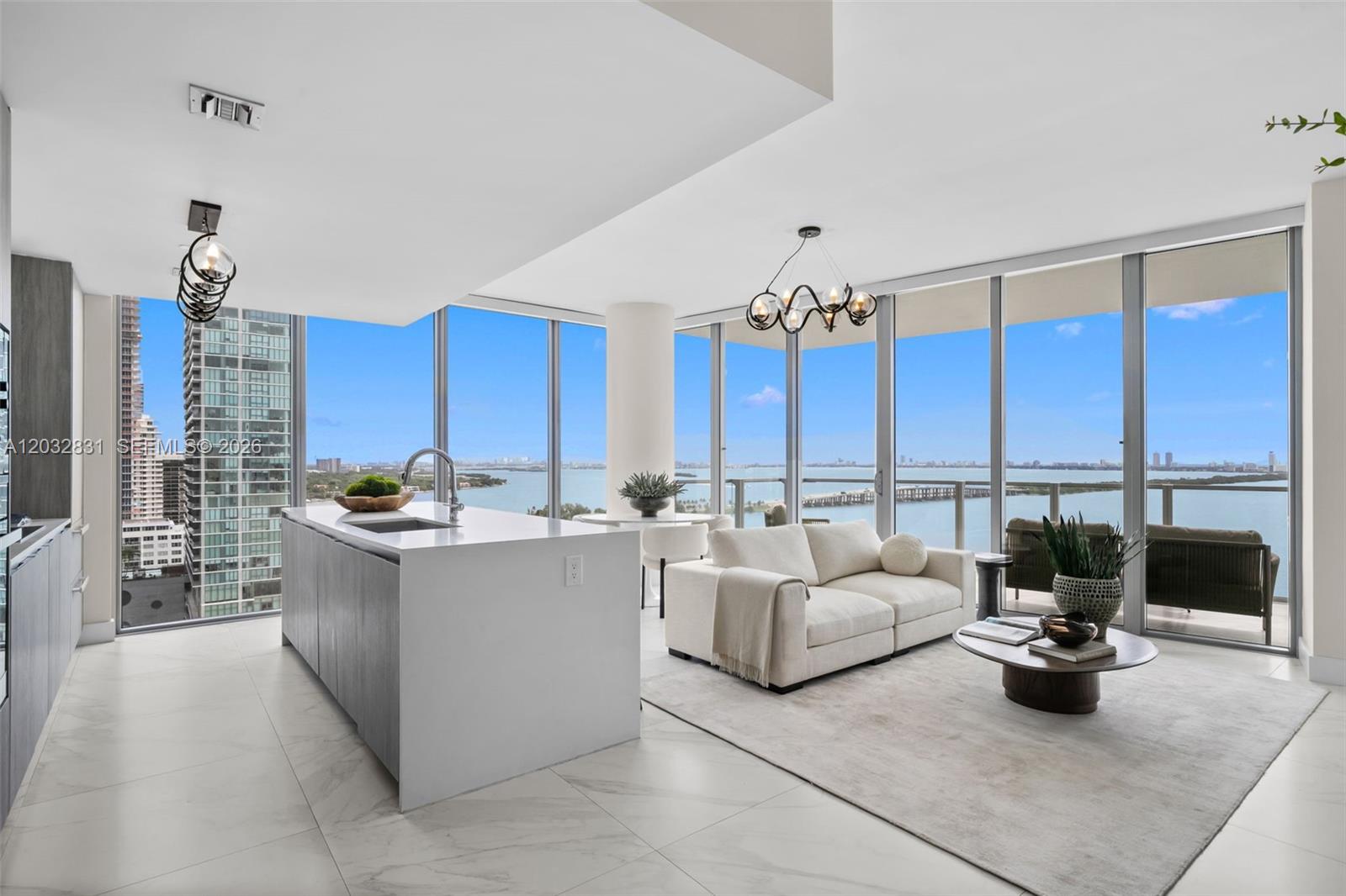 A modern kitchen and living area feature floor-to-ceiling windows with expansive water and city views — 2900 NE 7th Ave # 1902, Miami FL 33137, MIAMI, FL