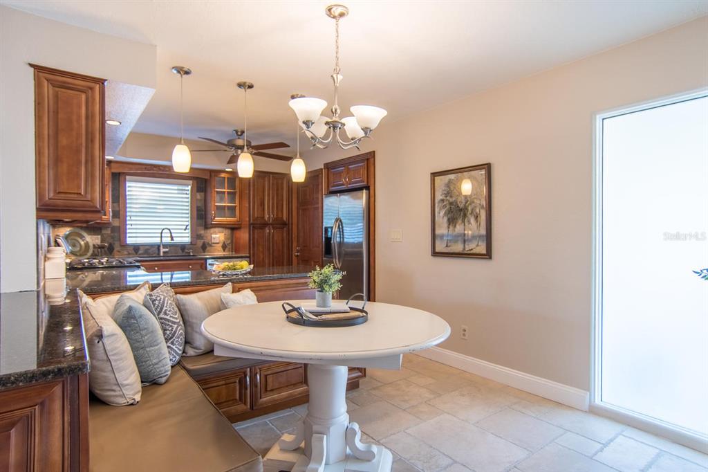 A kitchen features dark wood cabinetry, granite countertops, a built-in breakfast nook, and tile flooring — 542 59TH WAY S, ST PETERSBURG, FL