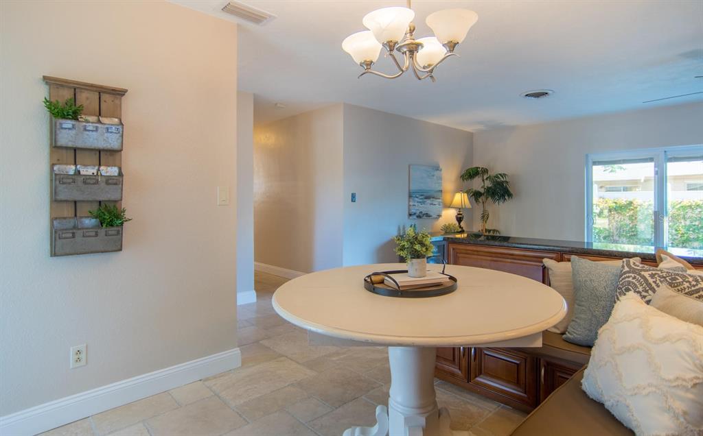 A dining area features a round table, a built-in bench, and a wall-mounted metal planter — 542 59TH WAY S, ST PETERSBURG, FL