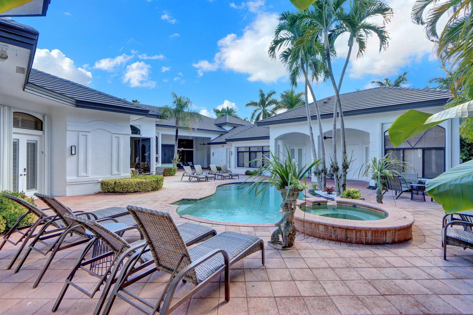 A swimming pool and hot tub sit on a tiled patio surrounded by a house — 3799 Coventry Lane, Boca Raton FL 33496, BOCA RATON, FL