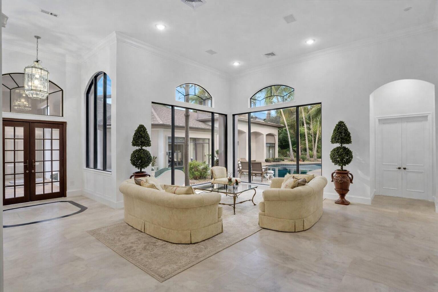 A bright living room with white walls, tile floors, large windows, and a pool view — 3799 Coventry Lane, Boca Raton FL 33496, BOCA RATON, FL