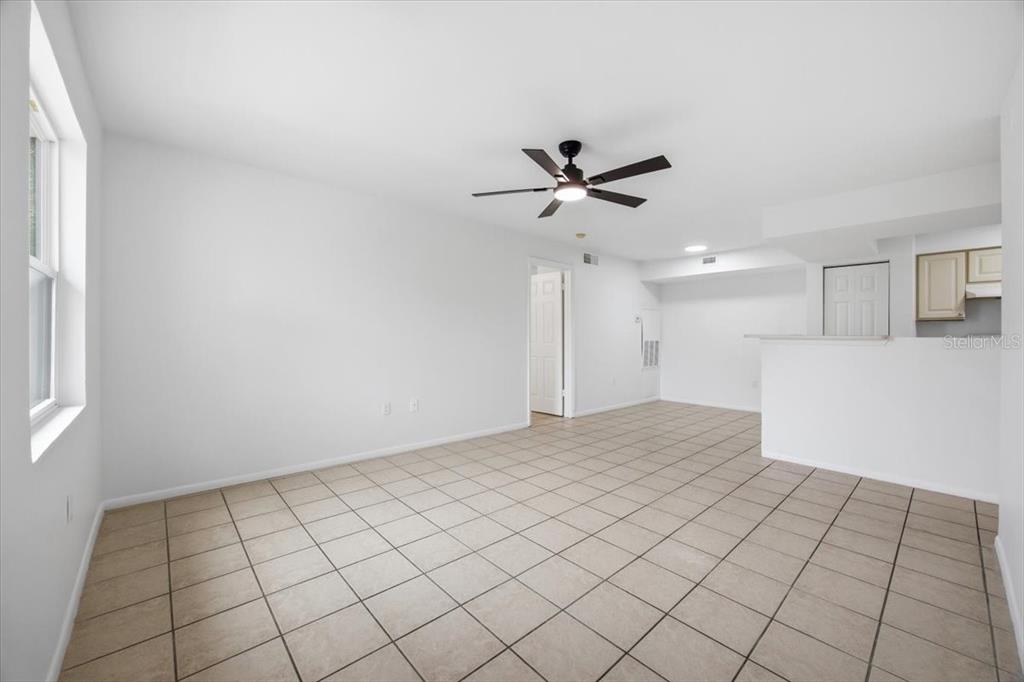 An empty living room features white walls, a ceiling fan, and light-colored tile flooring — 3028 PARKWAY BOULEVARD UNIT 301, KISSIMMEE, FL