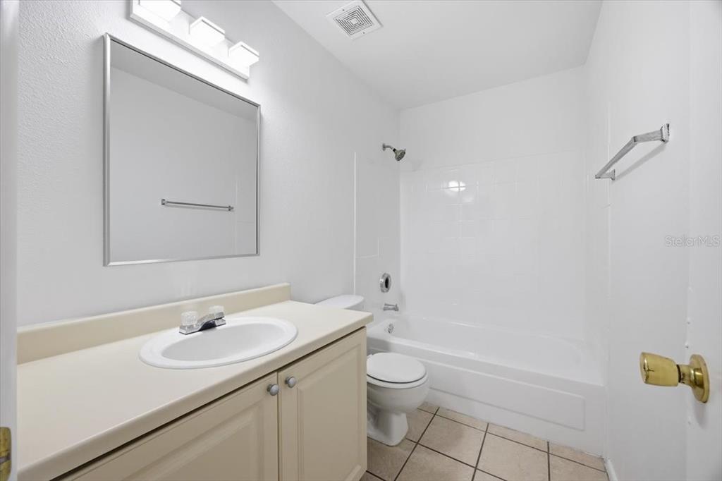 A bathroom features a vanity with a white sink, a toilet, and a tub-shower combo — 3028 PARKWAY BOULEVARD UNIT 301, KISSIMMEE, FL