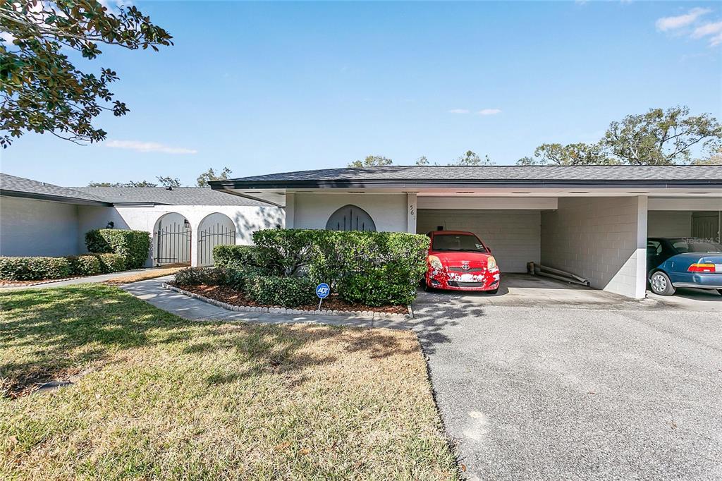 A single-story house exterior features a covered carport with two parked cars and landscaping — 561 E ORANGE STREET, ALTAMONTE SPRINGS, FL