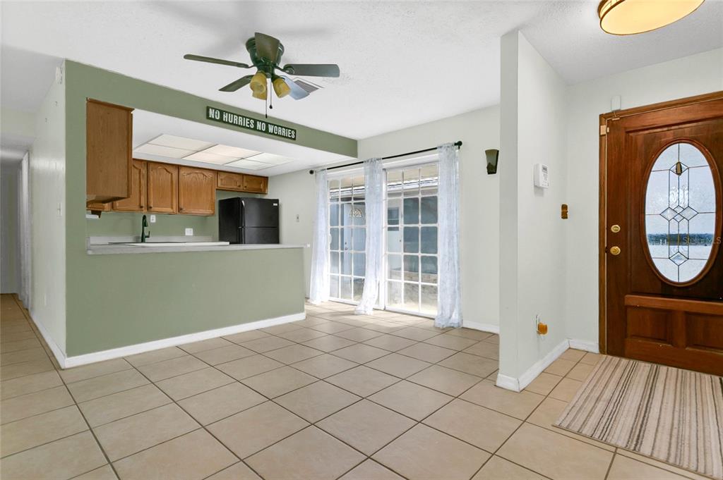 An open-concept dining area features tile flooring, a ceiling fan, and a kitchen pass-through — 561 E ORANGE STREET, ALTAMONTE SPRINGS, FL