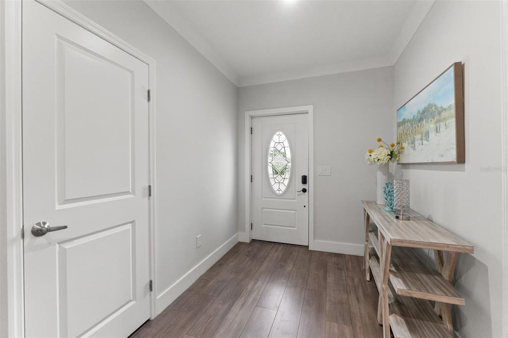 An entryway features light gray walls, wood-look flooring, a white front door, and a console table — 3040 BELCHER ROAD, DUNEDIN, FL