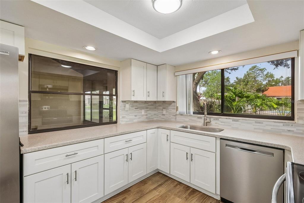 A kitchen with white cabinets, stainless steel appliances, a tile backsplash, and a large window — 107 SEVILLE COURT N, PLANT CITY, FL