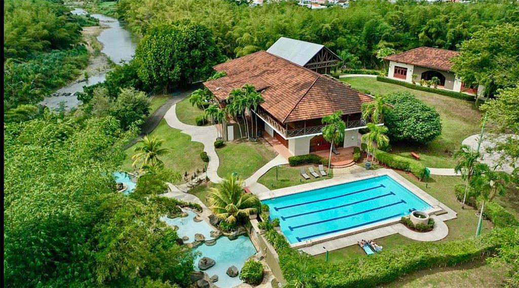 An aerial view of a house with a tiled roof, swimming pool, and adjacent river — 283 CAMINO DEL MANGO, GURABO, PR