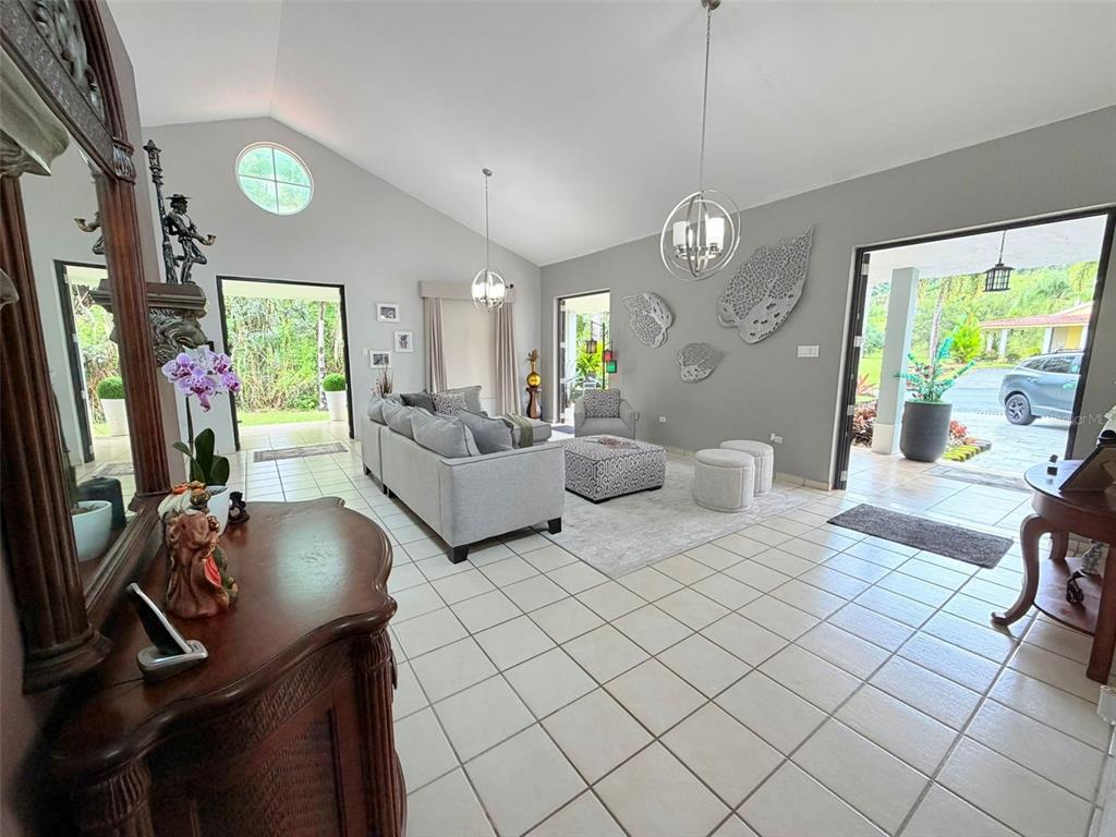 A bright living room with vaulted ceilings, tile floors, and open doorways leading outdoors — 283 CAMINO DEL MANGO, GURABO, PR