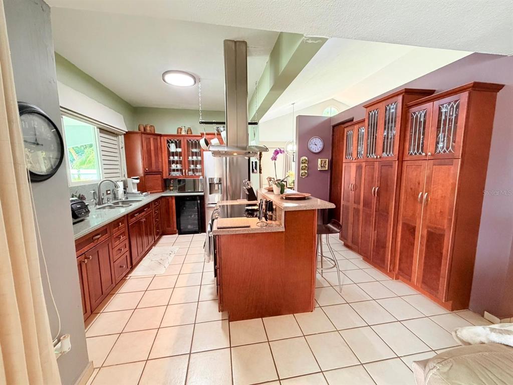 A kitchen features wood cabinetry, a center island with a range hood, and tile flooring — 283 CAMINO DEL MANGO, GURABO, PR