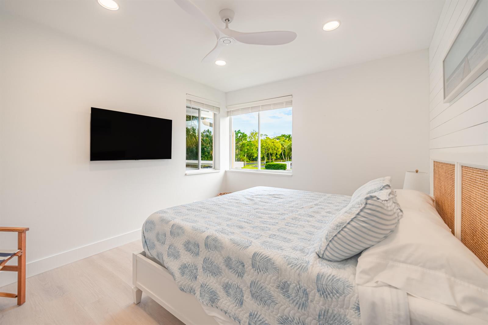 A bedroom features a bed with a patterned quilt, a wall-mounted television, and large windows — 353 S Us Highway 1 # A6, Jupiter FL 33477, JUPITER, FL
